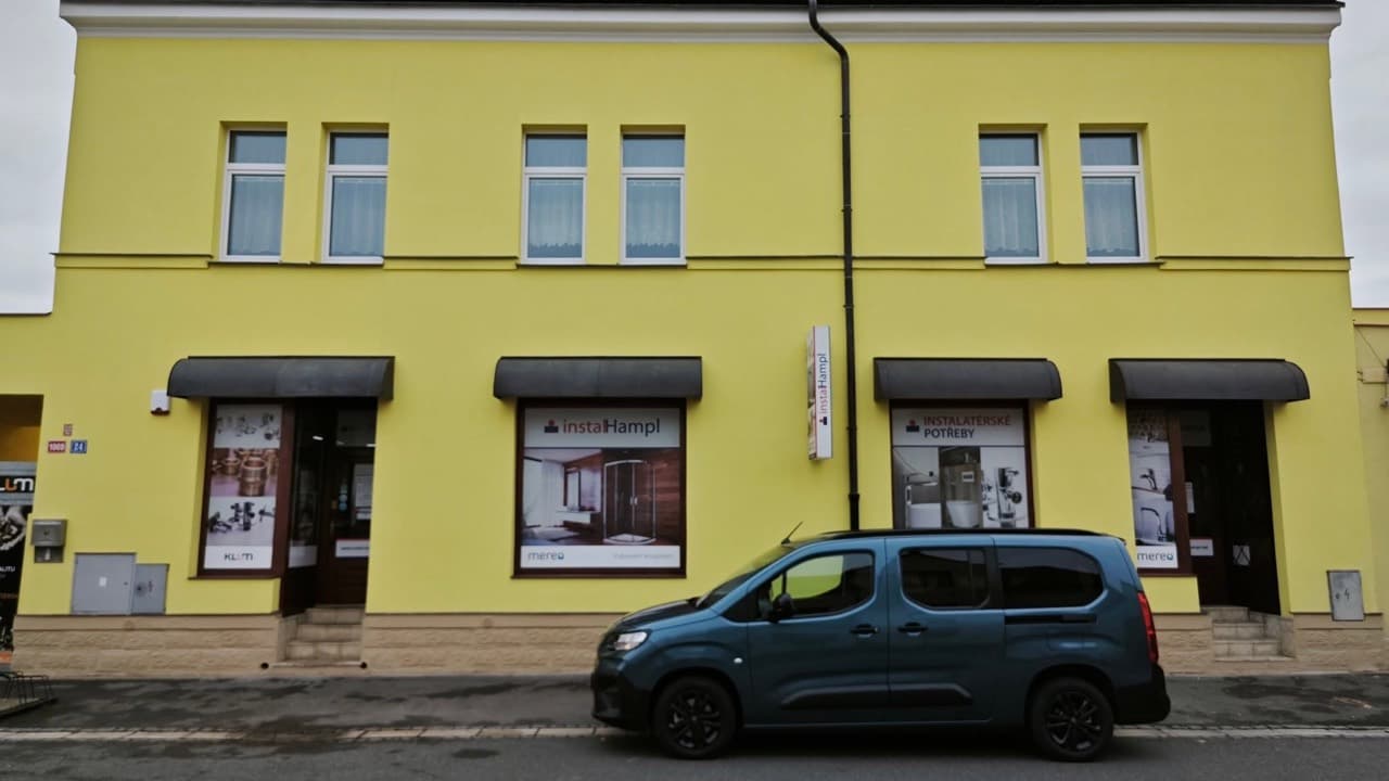 Žlutá budova prodejny Instalatérství Hampl v Nymburce s výlohami instalHampl a Instalatérské potřeby